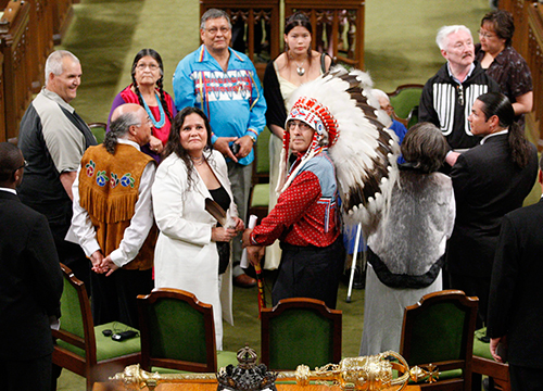 Onze leaders, survivantes et survivants autochtones forment un cercle sur le terrain du Parlement à l’occasion de la présentation des excuses du gouvernement canadien.