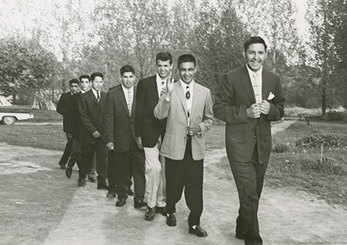 Photo des années 1950 ou 1960 d’une rangée de sept adolescents autochtones portant des costumes et souriant.