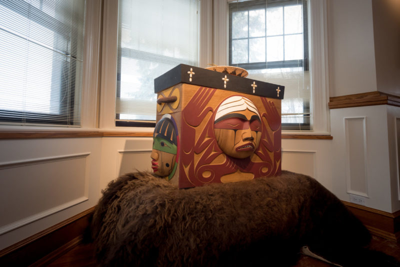 Bentwood Box sitting on animal pelt displayed on plinth