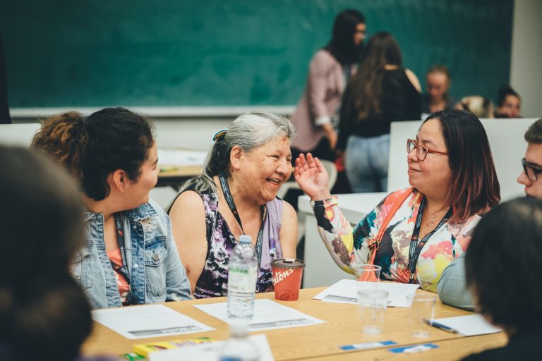 Groupe de personnes assises à une table et discutant.