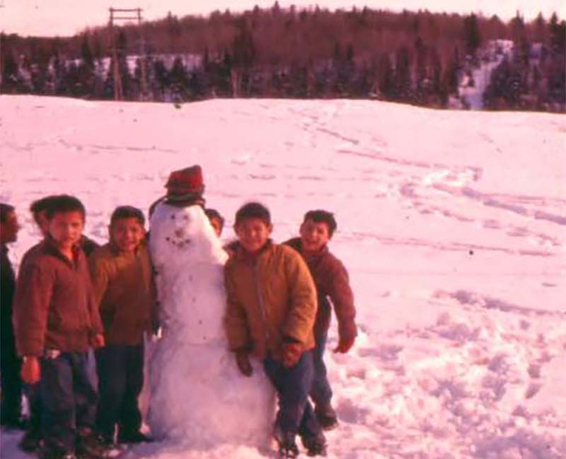 Children from Cecilia Jeffrey school outside building a snowman 