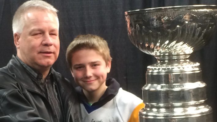 Blind golfer Gerry Nelson and his son Wyatt beside the Stanley Cup. Nelson introduced Eugene Arcand to Gordie Howe.