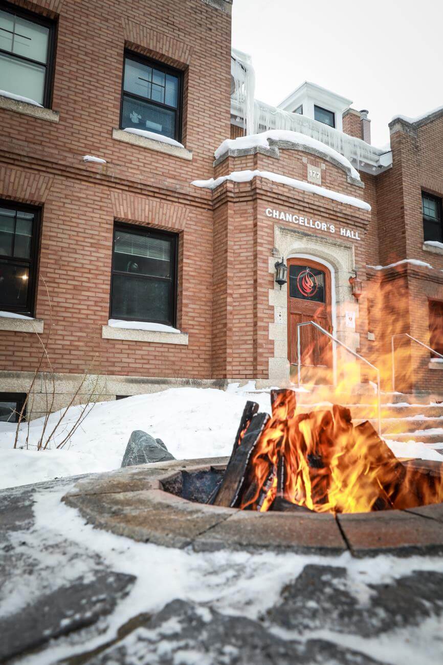 L’édifice du Centre national pour la vérité et la réconciliation en hiver avec un feu dans un foyer circulaire.