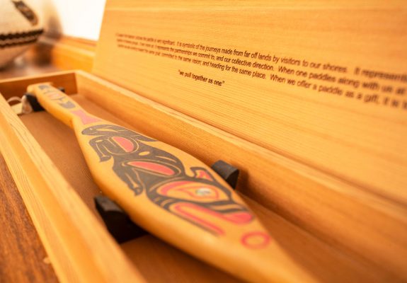 A paddle and its inscribed cedar box, along with a second paddle, presented by the Pulling Together Canoe Society as a symbol of reconciliation.