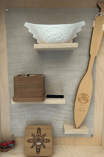 A display of artifacts, including a wooden paddle, a patterned bowl, and a wooden plaque.